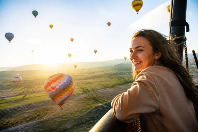 Gün doğumunda yeşil bir vadinin üzerinde rengârenk sıcak hava balonları